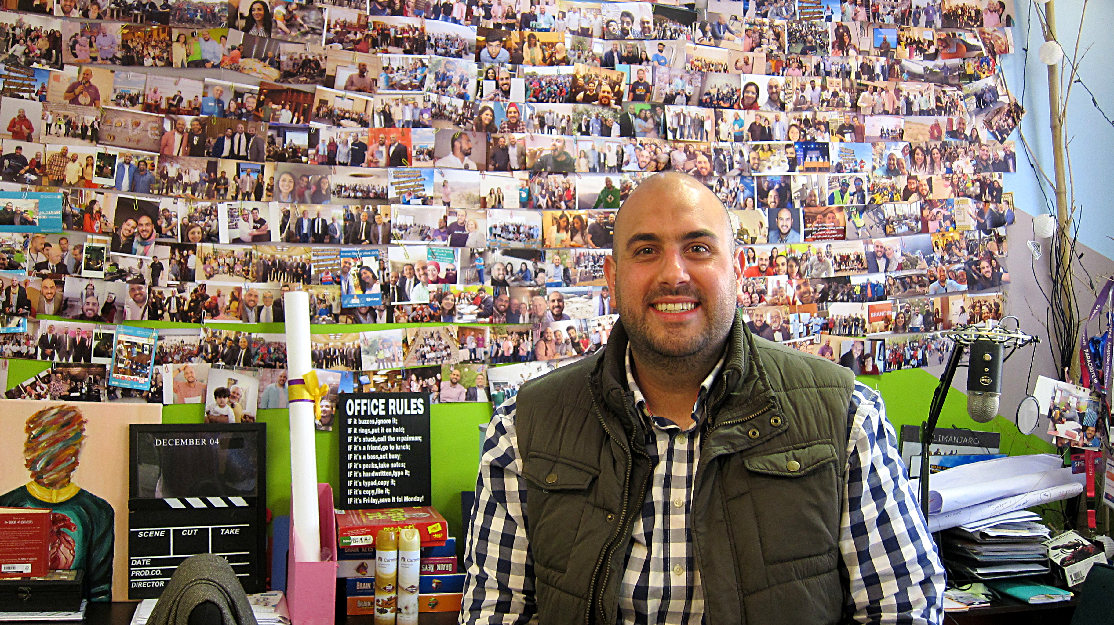 Ghassan Halawa in his Amman office, with a wall of photographs behind him