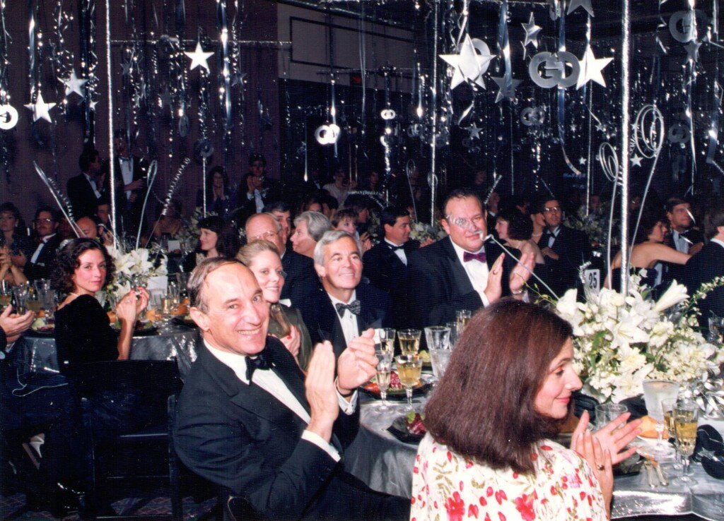 Gideon Gartner and guests applaud at Gartner Group’s tenth-anniversary party, beneath hanging stars and silver streamers.