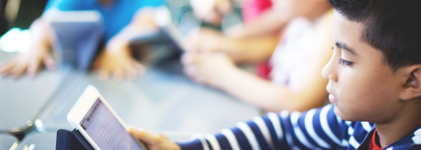A student concentrating on a tablet during a classroom reading session