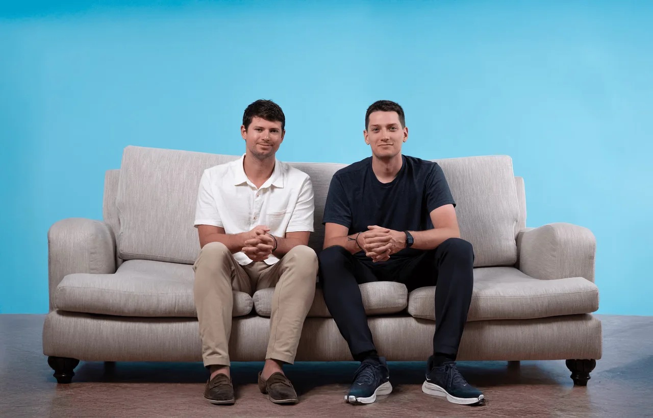 Giga Energy’s two founders seated together against a blue background