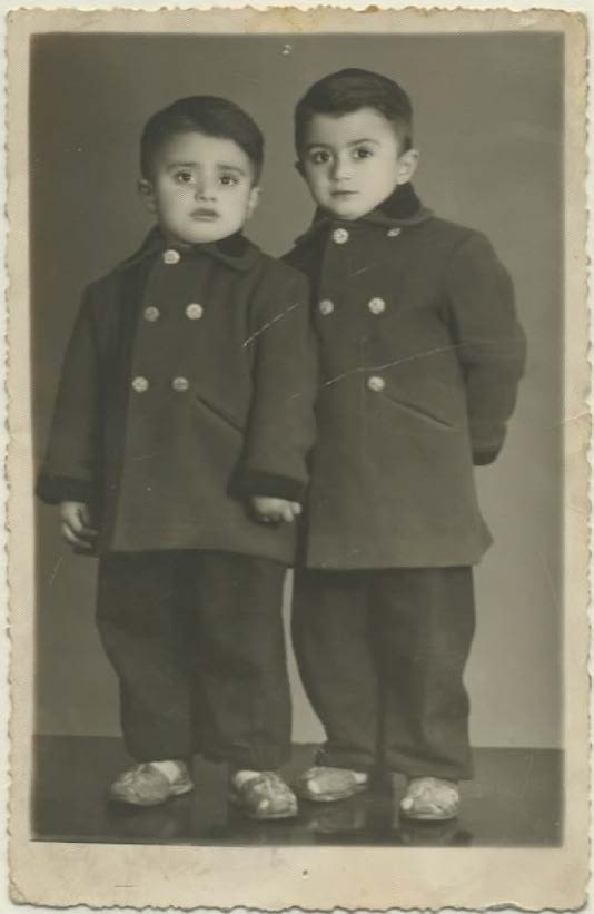 Childhood photograph of Jean Hakim on the left and Gilbert Hakim on the right, both wearing buttoned coats