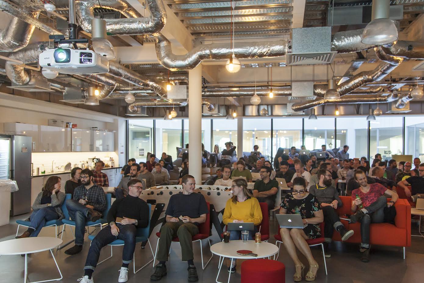 Brandwatch colleagues gathered in an open office, in a photograph from the company’s 2015 funding announcement