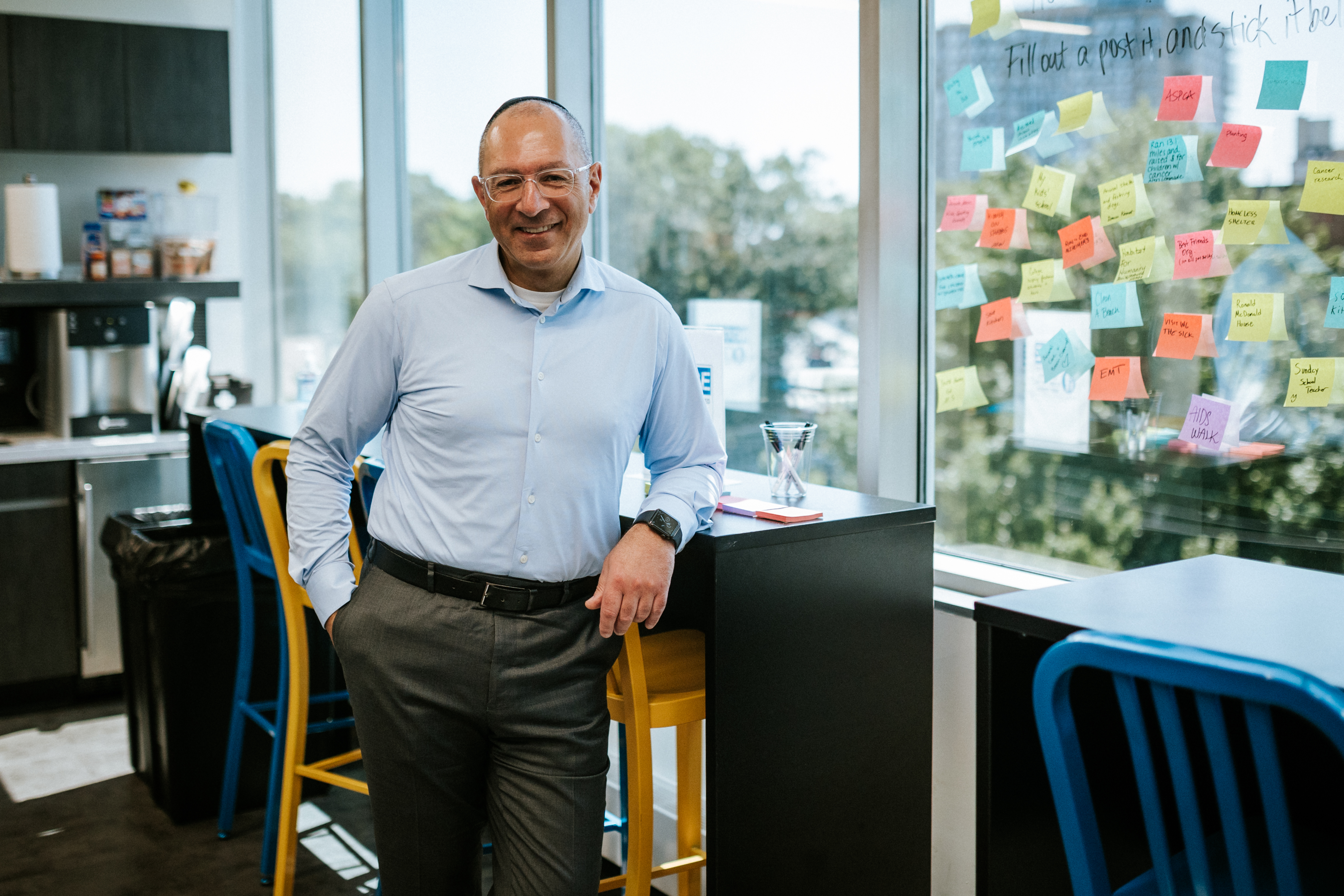 Gilles Gade standing in an office beside a glass wall covered in colourful notes