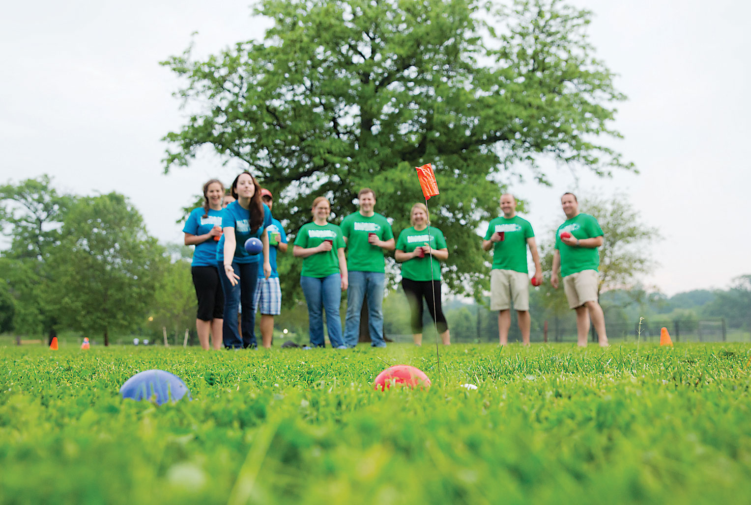 Baltimore bocce players watch a ball being rolled across the grass