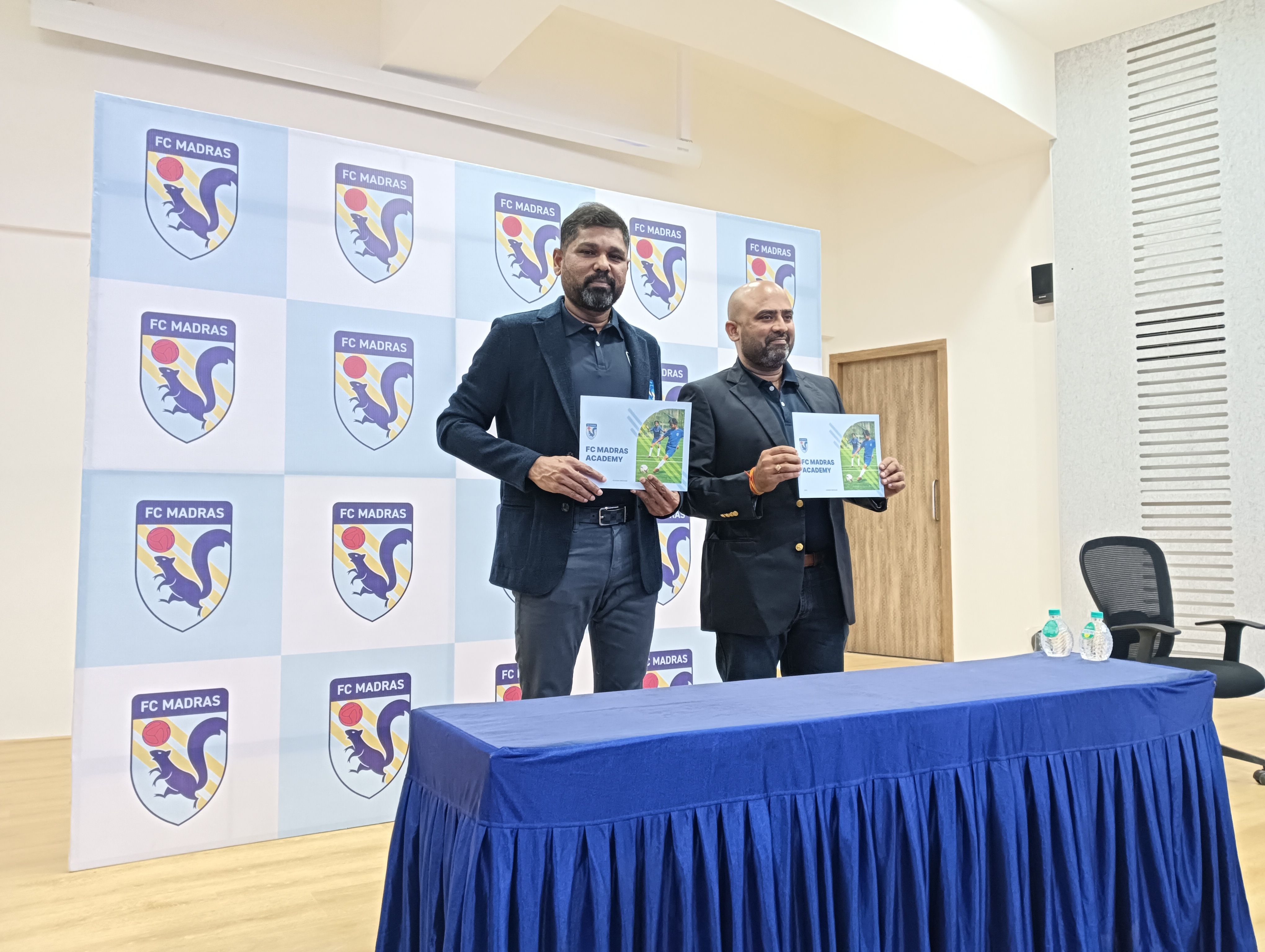 Girish Mathrubootham, left, and a colleague holding FC Madras Academy brochures at the 2023 launch