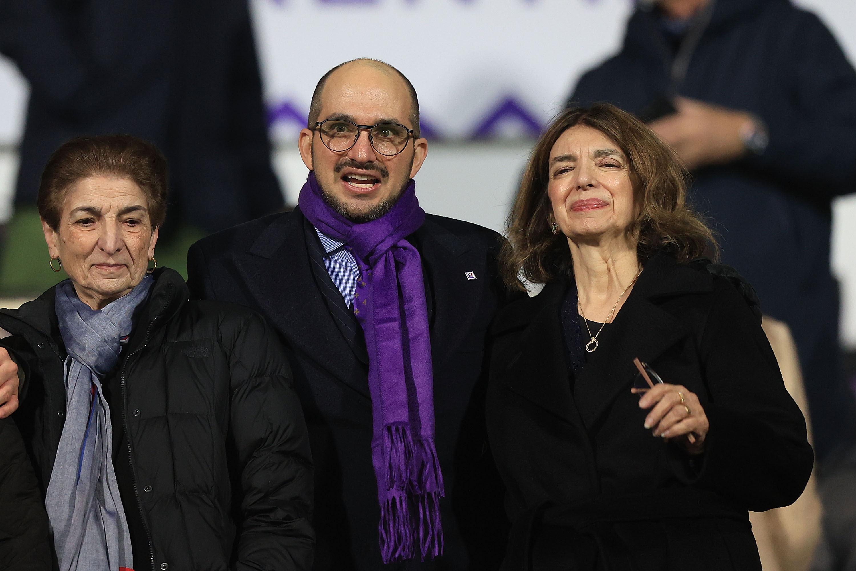 Giuseppe Commisso, wearing glasses and a purple scarf, with companions at the Fiorentina versus Como Coppa Italia match