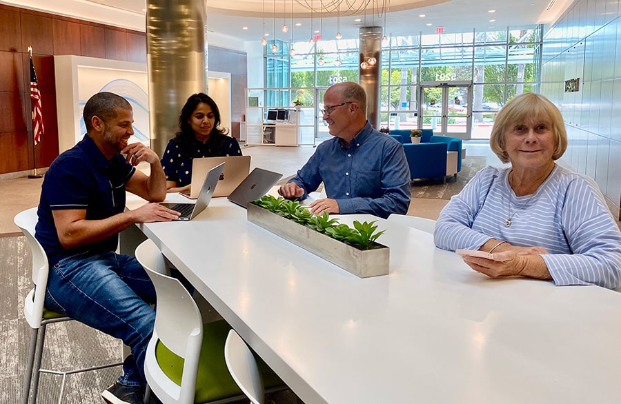 Four people gathered around laptops at a table in Glassbeam’s official team photograph