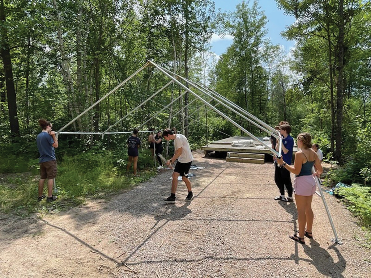 Young participants and adults assemble replacement platform tents at Camp Northern Lights