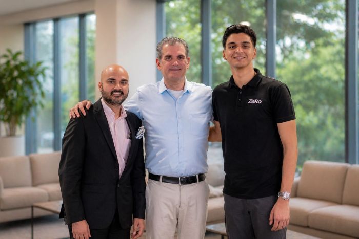 Umesh Sharma, Glenn Turner and Manit Deep Prashar stand together in a bright lobby.