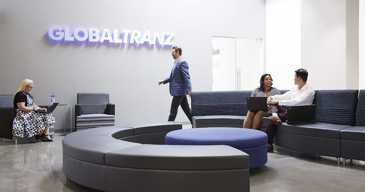 Employees working in the GlobalTranz office lobby beneath the company name