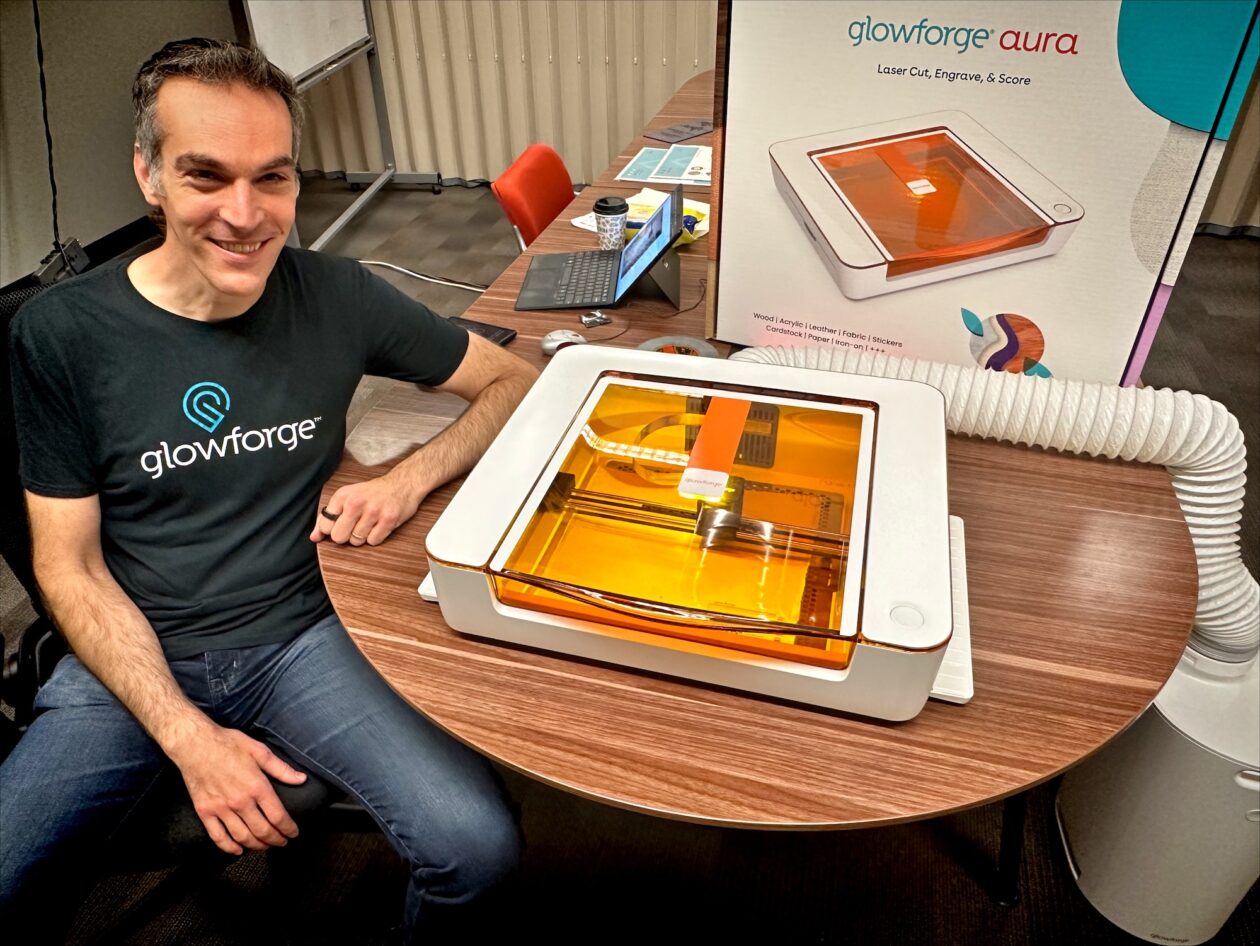 Dan Shapiro sitting beside the orange-lidded Glowforge Aura in 2023