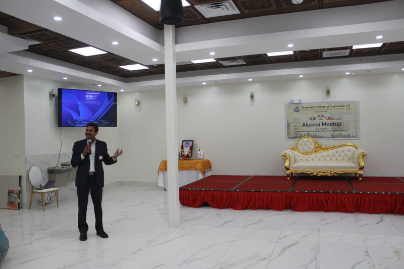 Gopal Krishnamurthy speaking with a microphone at a Thiagarajar College of Engineering alumni gathering