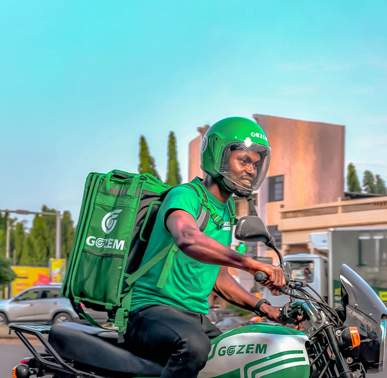 Gozem courier on a motorcycle wearing a helmet and carrying a green delivery bag