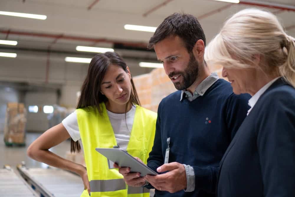 A GPS Insight employee showing a tablet to two warehouse workers