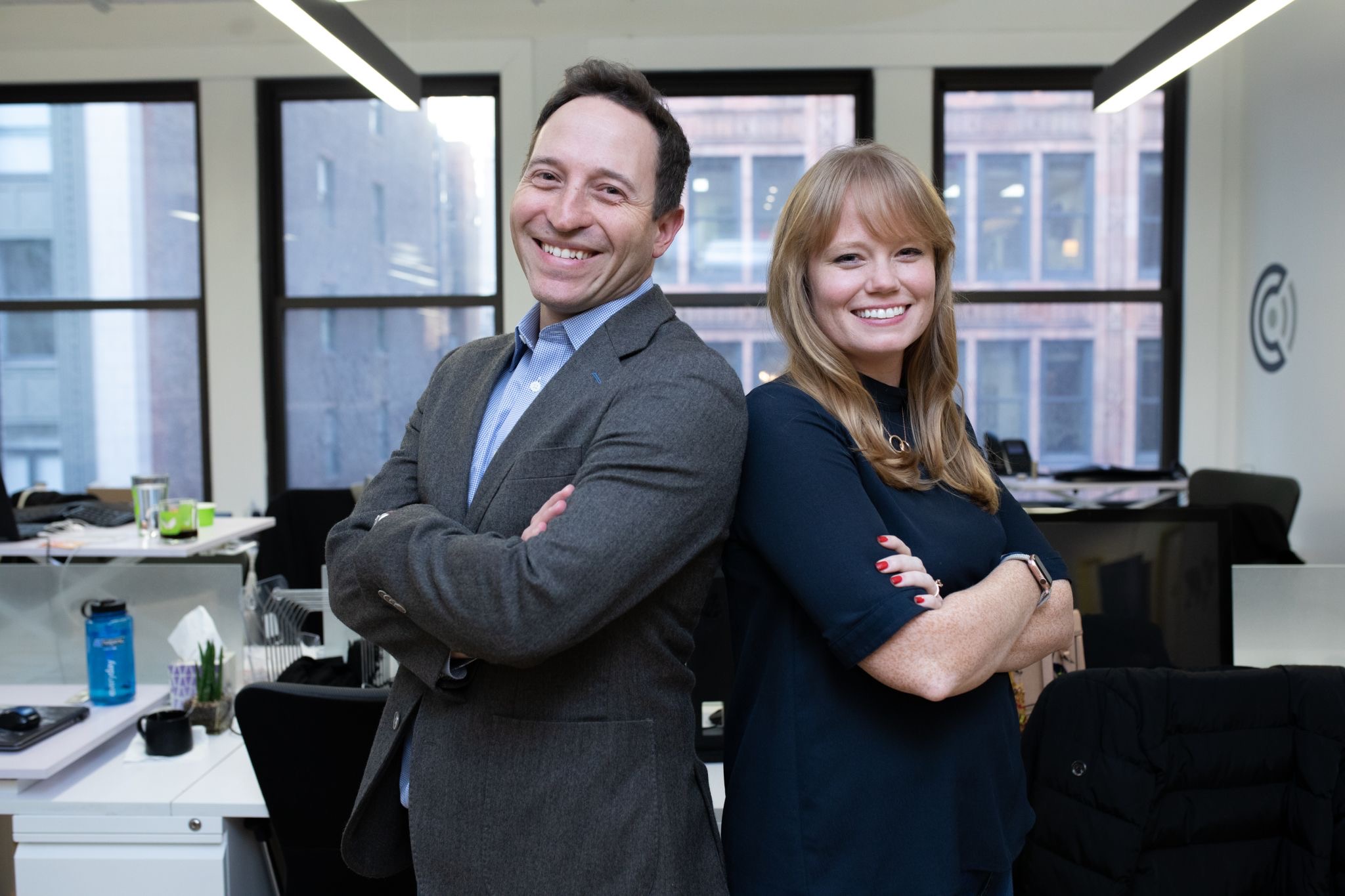 Harvey Hudes and Grace Keith Rodriguez standing back to back in an office