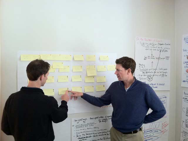 Graham Weaver, at right, discussing a wall of sticky notes with a founding partner during a 2011 process-mapping session