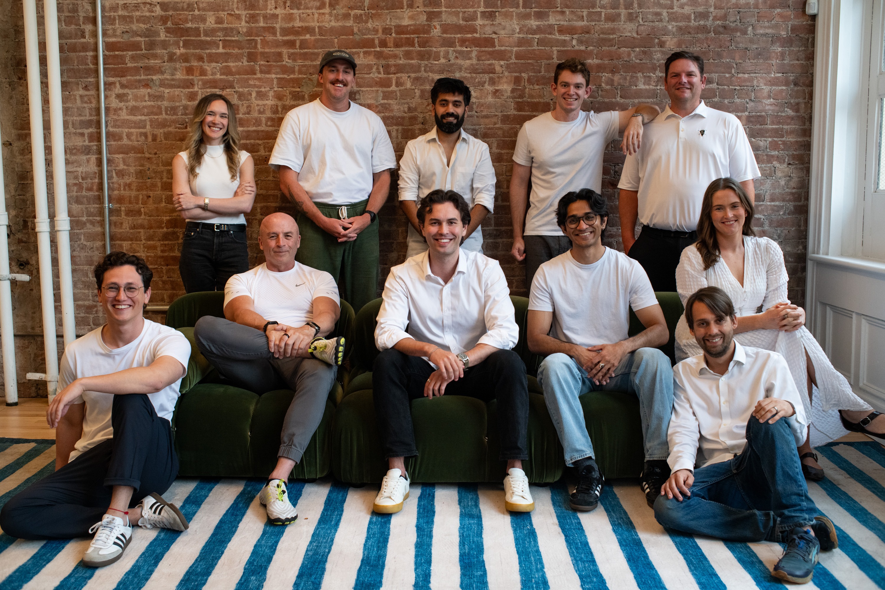 The GrailPay team gathered in front of a brick wall in its New York office