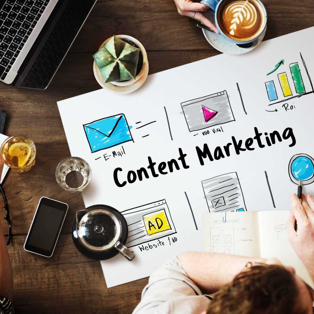 Content marketing illustration showing a laptop, coffee and a sheet of campaign sketches