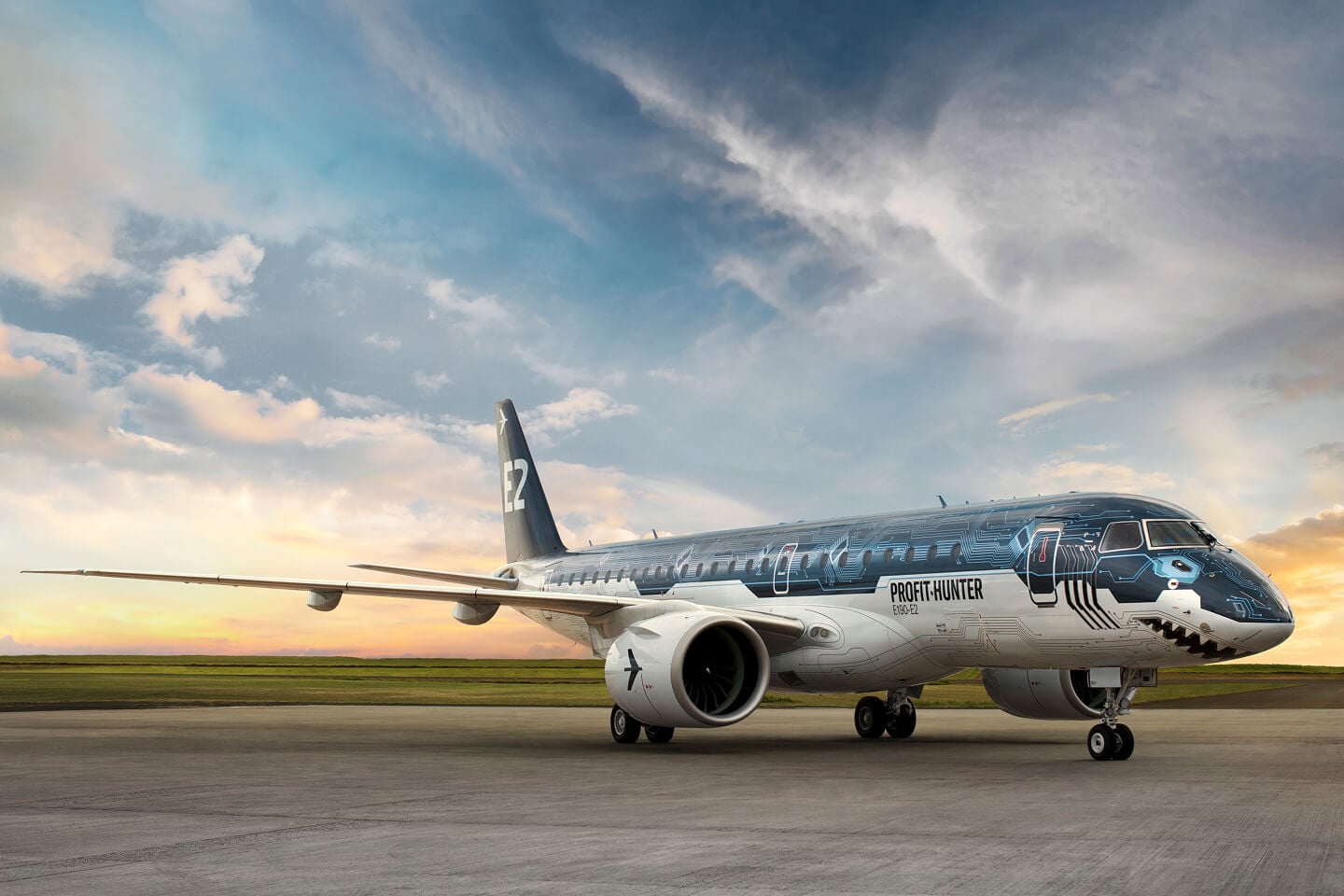 An Embraer Profit Hunter passenger jet painted with a shark design sits on a runway at sunset