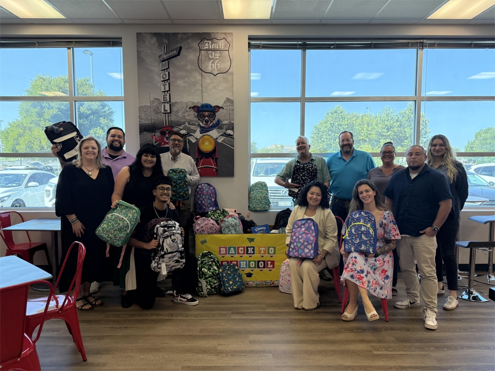 Gravity Lending team members standing together with backpacks and a back-to-school sign