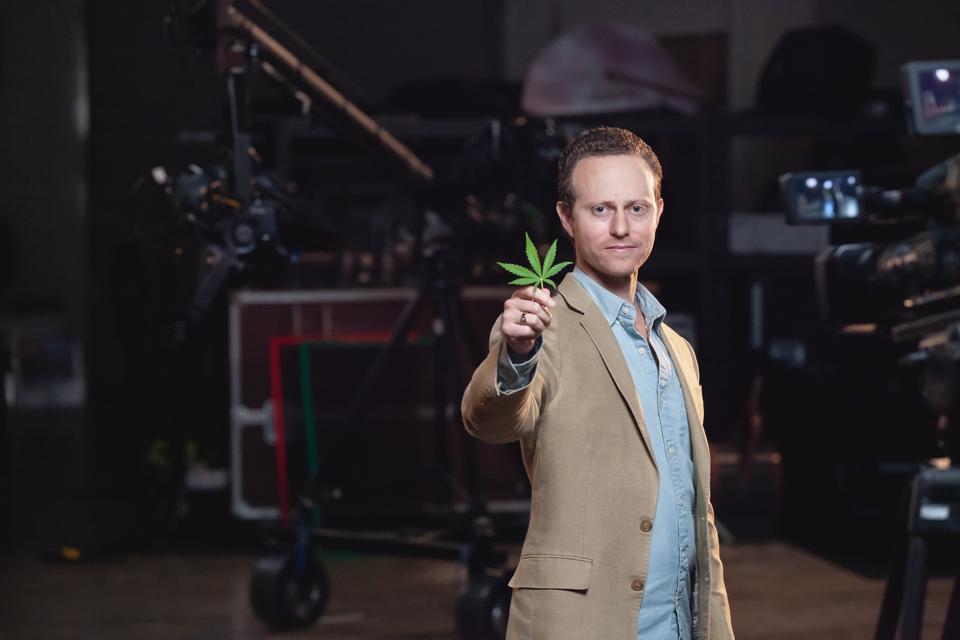 Green Flower founder Max Simon holding a cannabis leaf on a video set