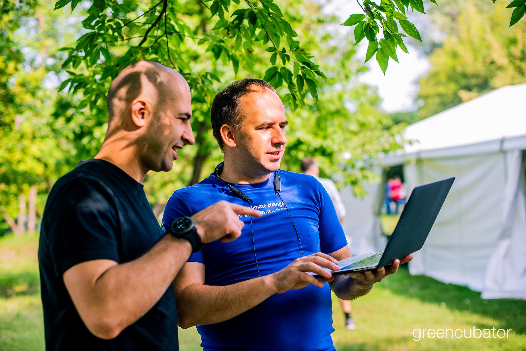 Two participants discussing work on a laptop at an outdoor Greencubator gathering