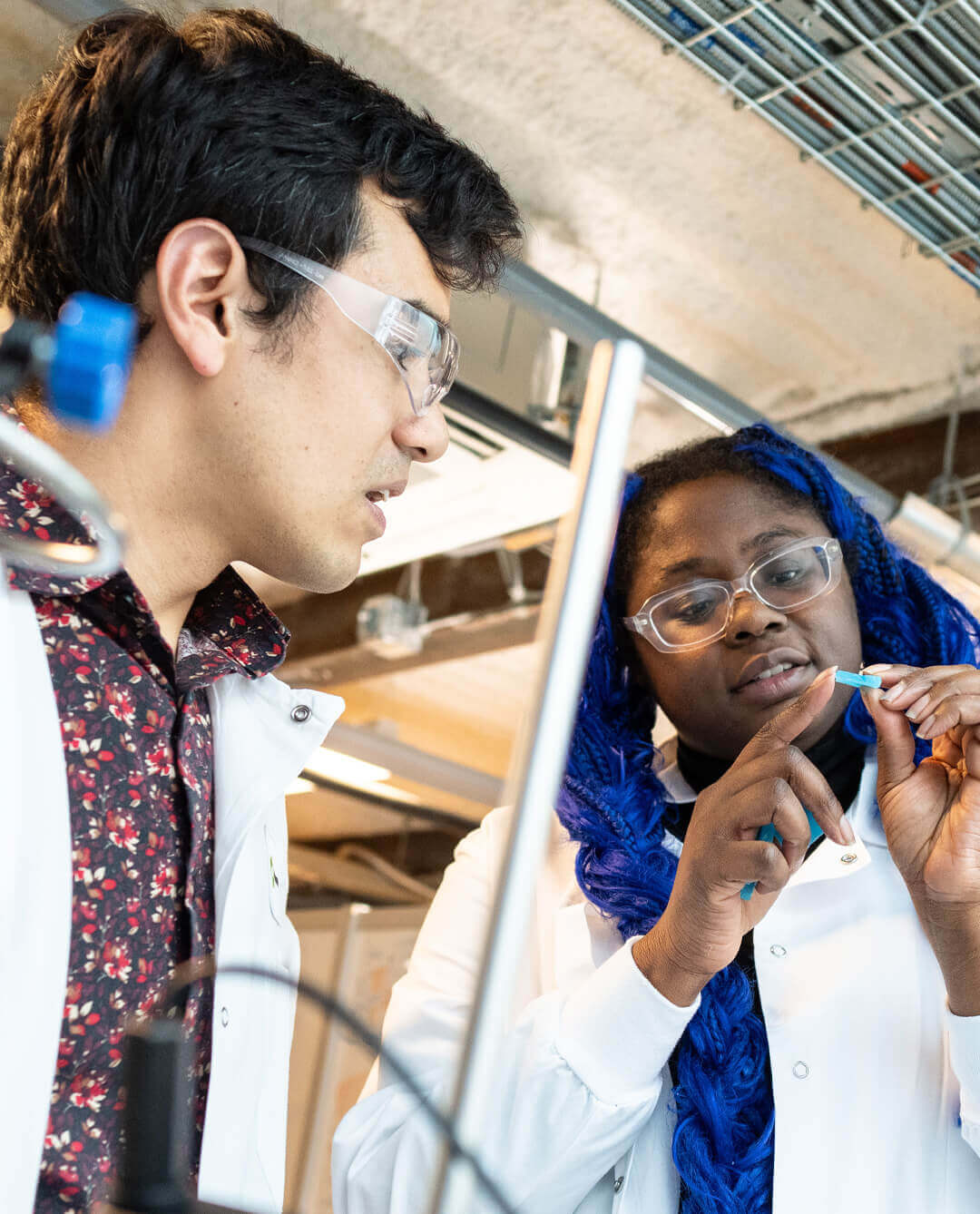 Two Greentown members in protective glasses examine a small material sample together