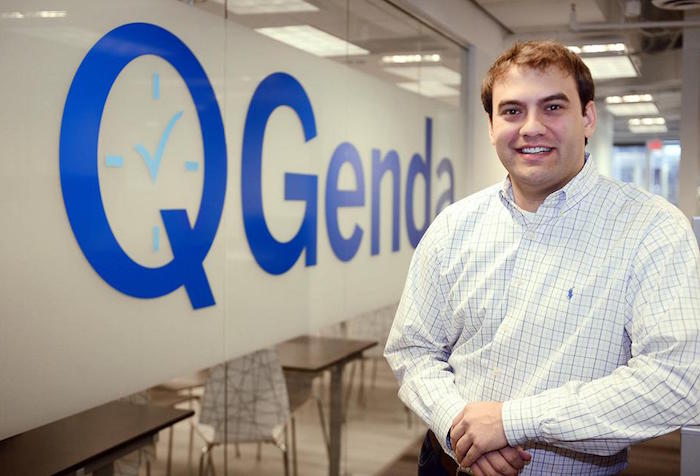 Greg Benoit standing beside the QGenda sign in the company’s office