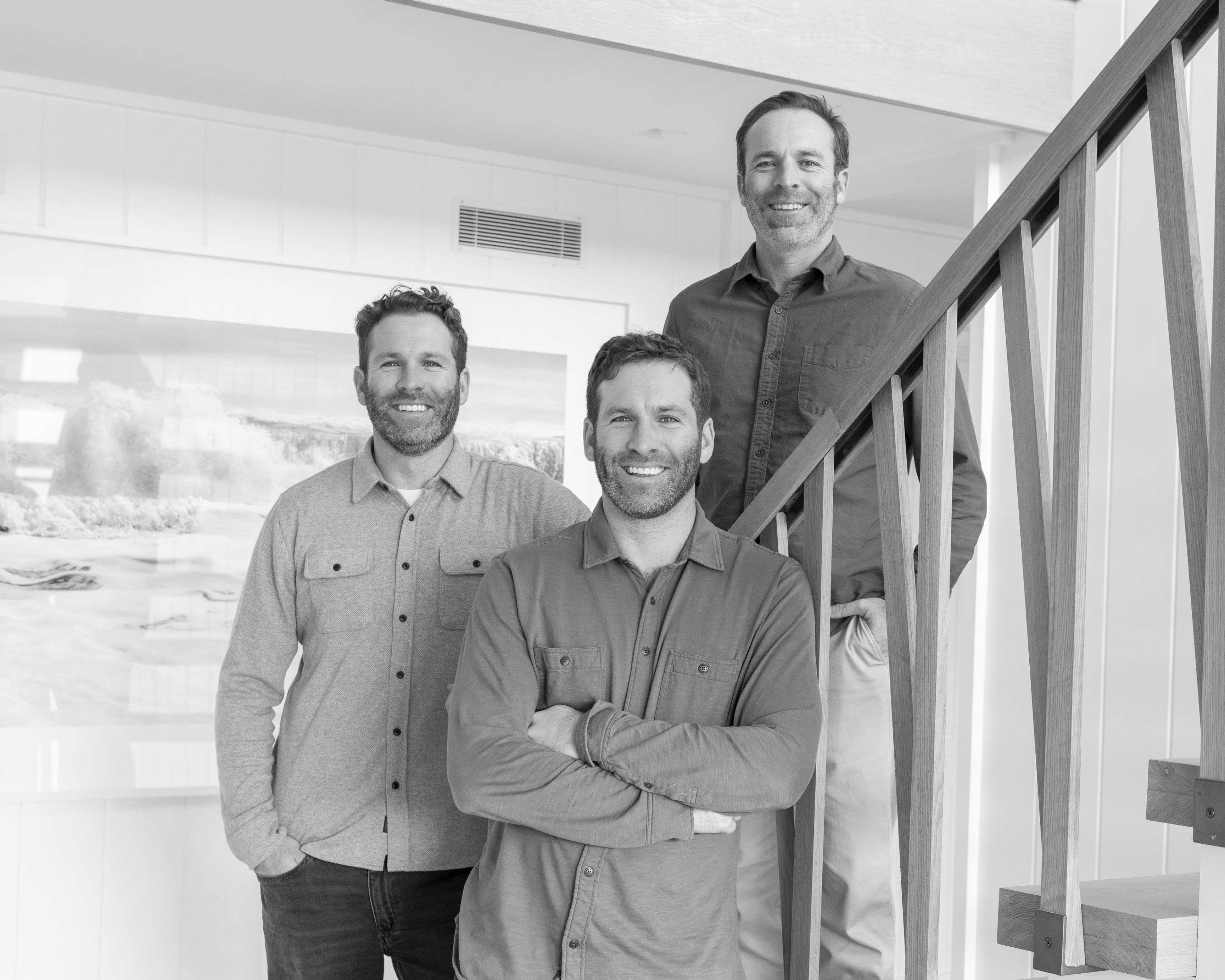 The three Burns brothers standing together beside a wooden staircase