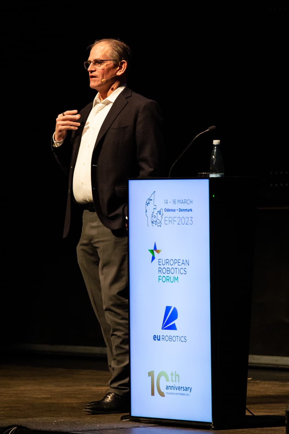 Greg Smith speaking beside the European Robotics Forum lectern in Odense in March 2023