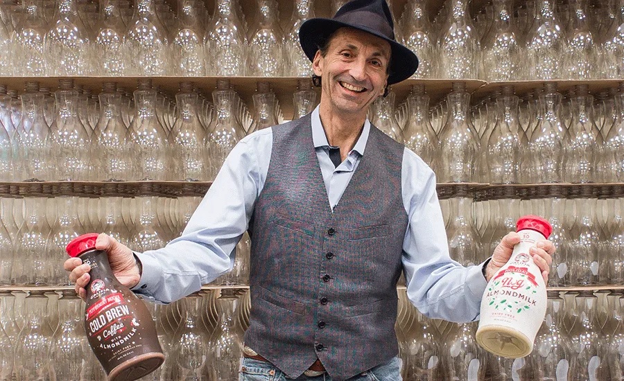 Greg Steltenpohl holding two Califia Farms drinks in front of shelves of glasses