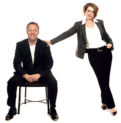 Greg Walthour seated beside Darcie Walthour, who is standing with one hand on his shoulder