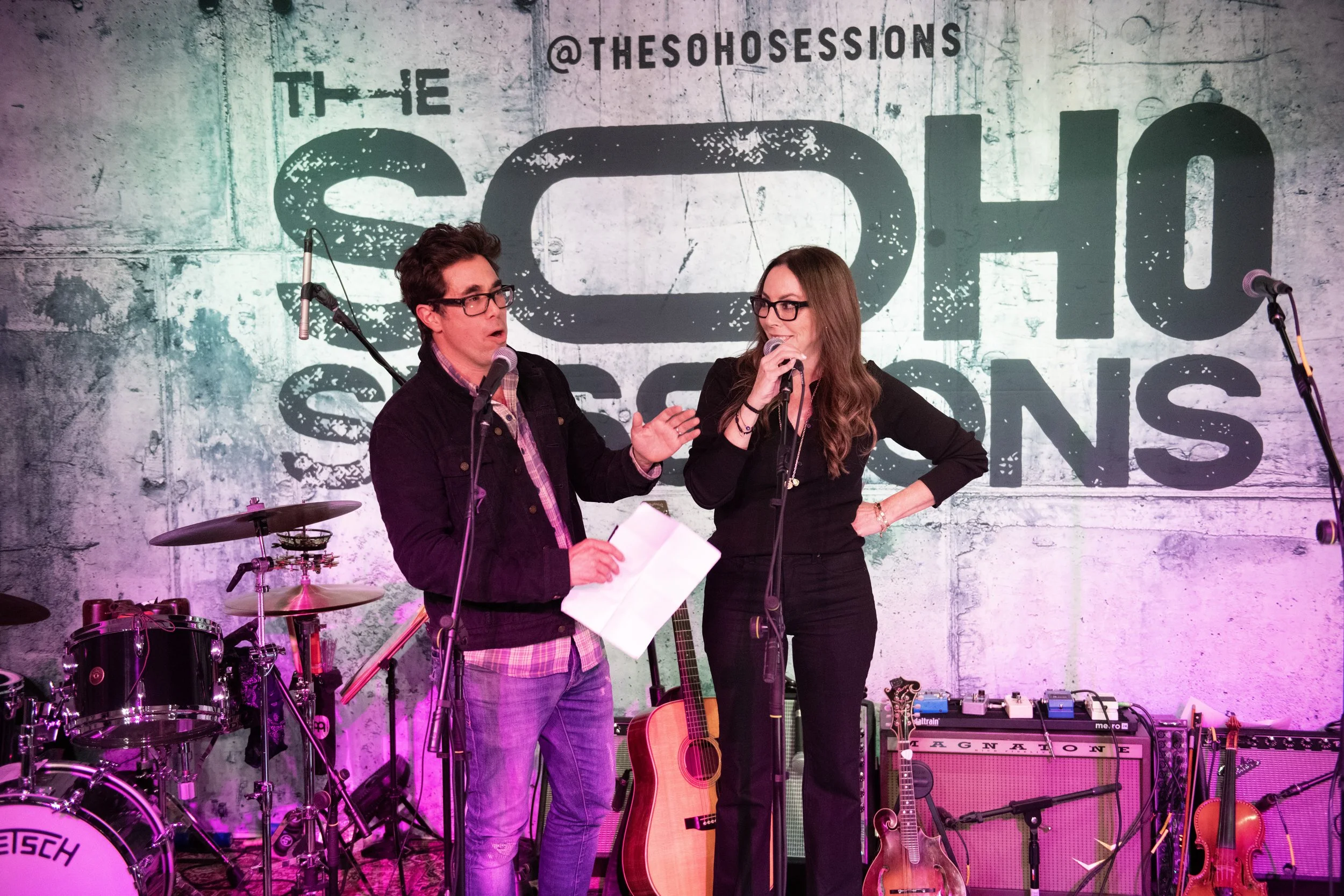 Greg Williamson, left, and Nicole Rechter speaking into microphones on The Soho Sessions stage