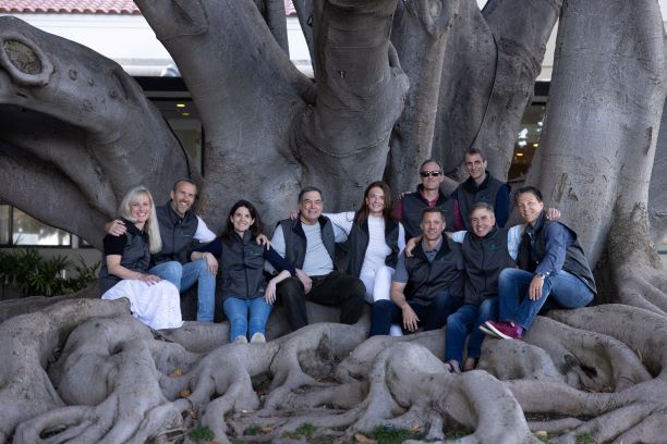Gregg Dixon and Voltus leadership colleagues gathered among the broad roots of a tree