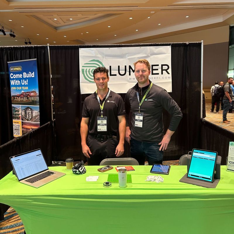 Gregory Fast and Adam Domingue standing at Lumber's booth during a construction industry event