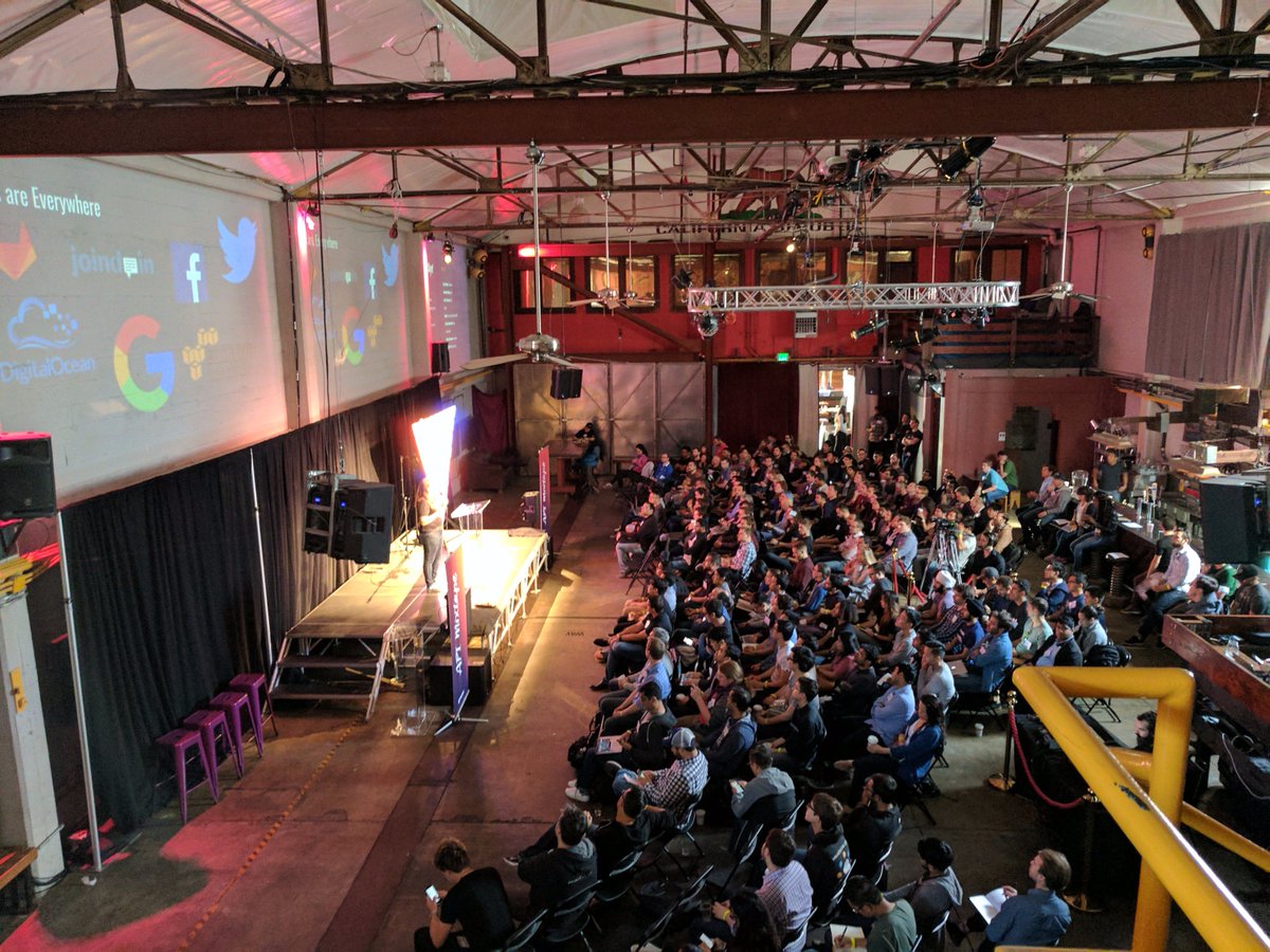 An audience seated in an industrial event space at the first API Mixtape conference