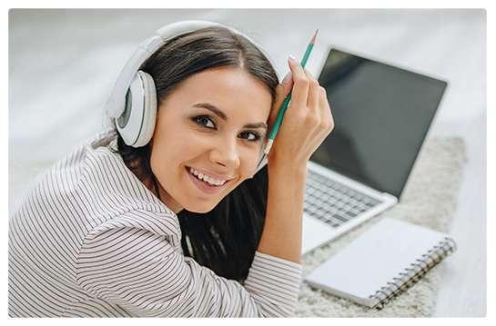 Growing Stars promotional photograph showing a learner with headphones, a notebook, and a laptop