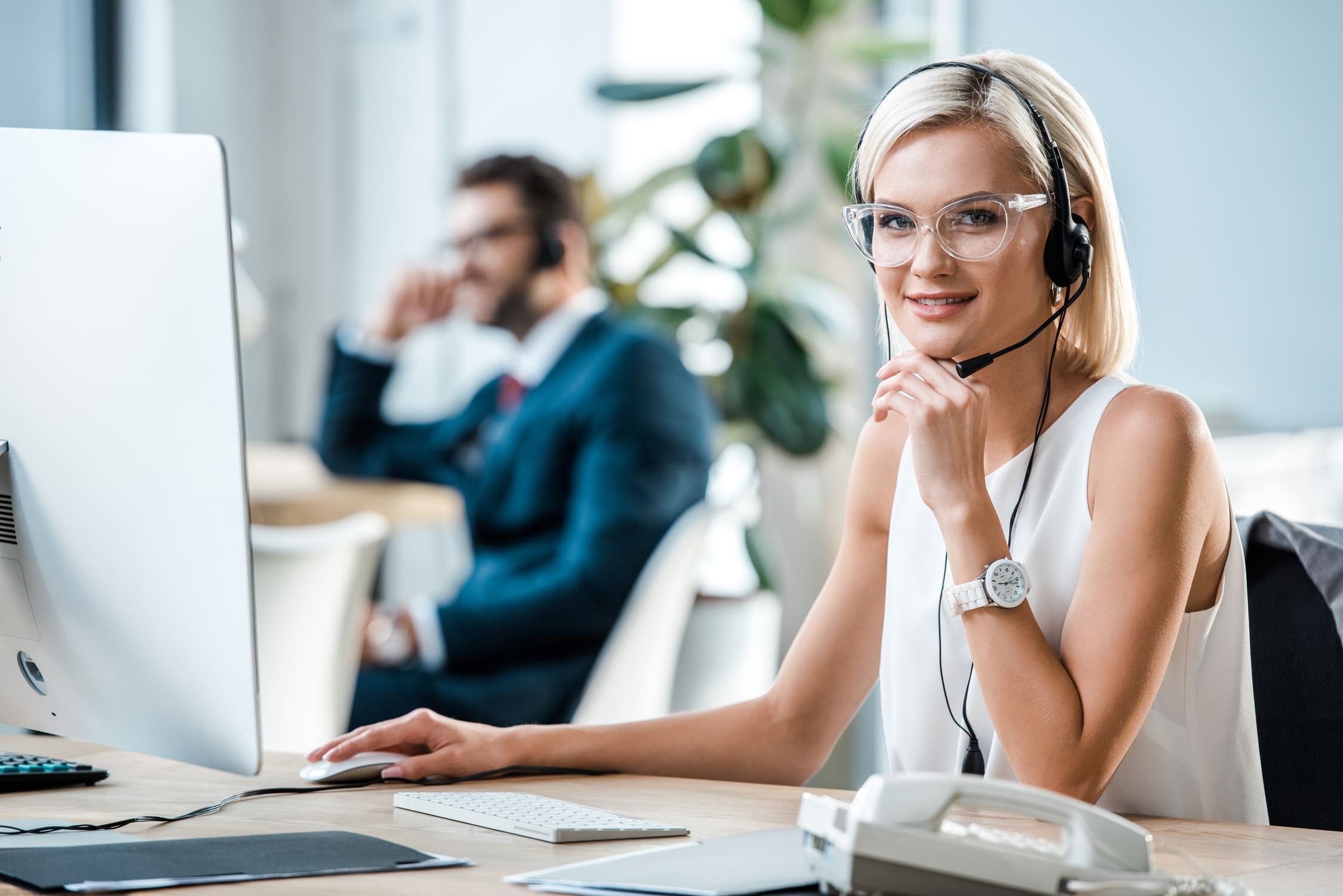 Illustrative office photograph of a headset-wearing sales representative at a computer