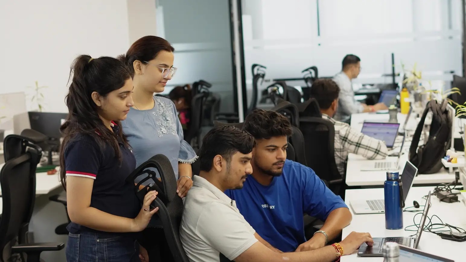 Growth Natives colleagues gathered around a laptop in the office