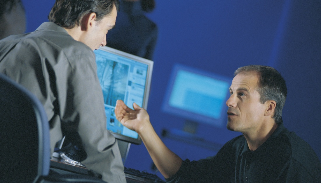 Two people discussing a computer-based training display