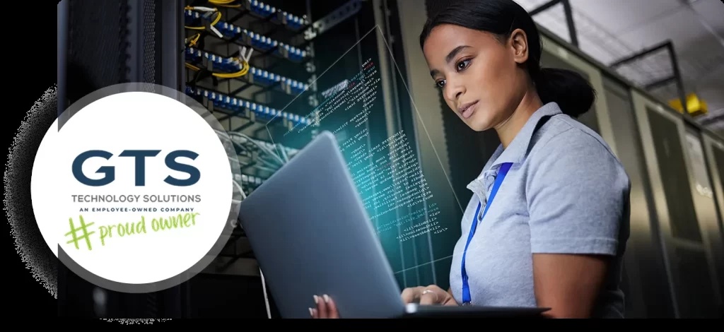 A technician checking a laptop beside server equipment in a company-published illustrative photograph.