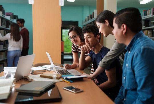 A group gathered around laptops at a shared table