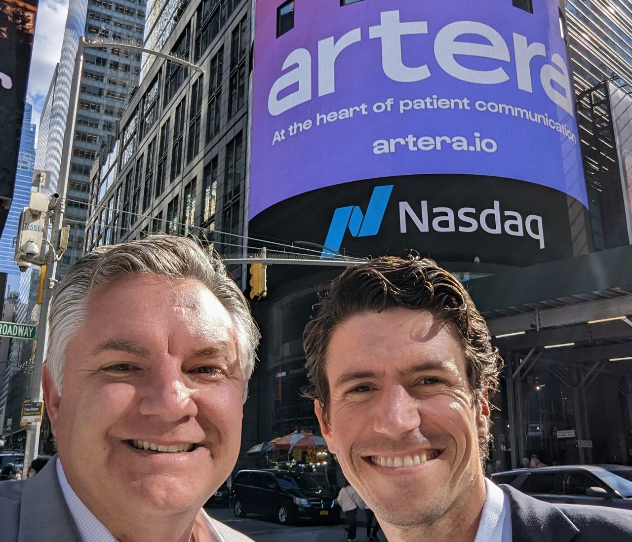Guillaume de Zwirek, right, with a colleague beneath the Nasdaq display showing Artera’s new name in Times Square