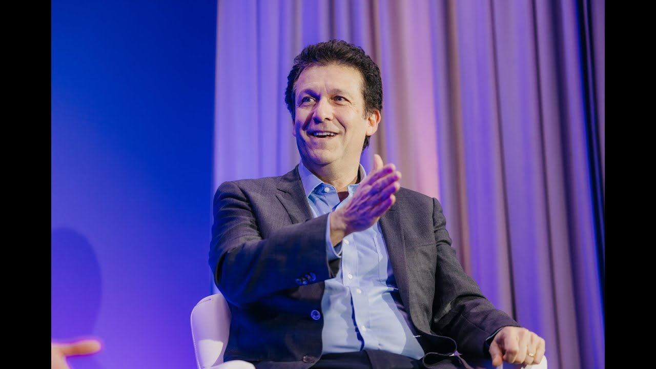 Guillaume Pfefer speaking during a Flagship CEO interview, seated against blue and purple curtains