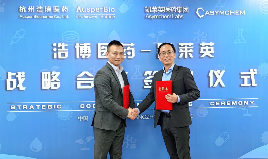 Guofeng Cheng and an Asymchem executive shake hands while holding red agreement folders at a strategic cooperation signing ceremony