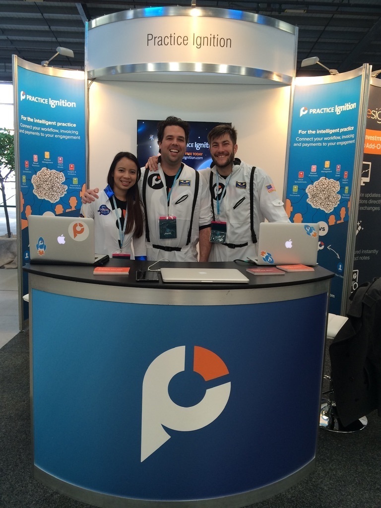 Guy Pearson and the early Practice Ignition team in white spacesuits at a conference exhibition stand