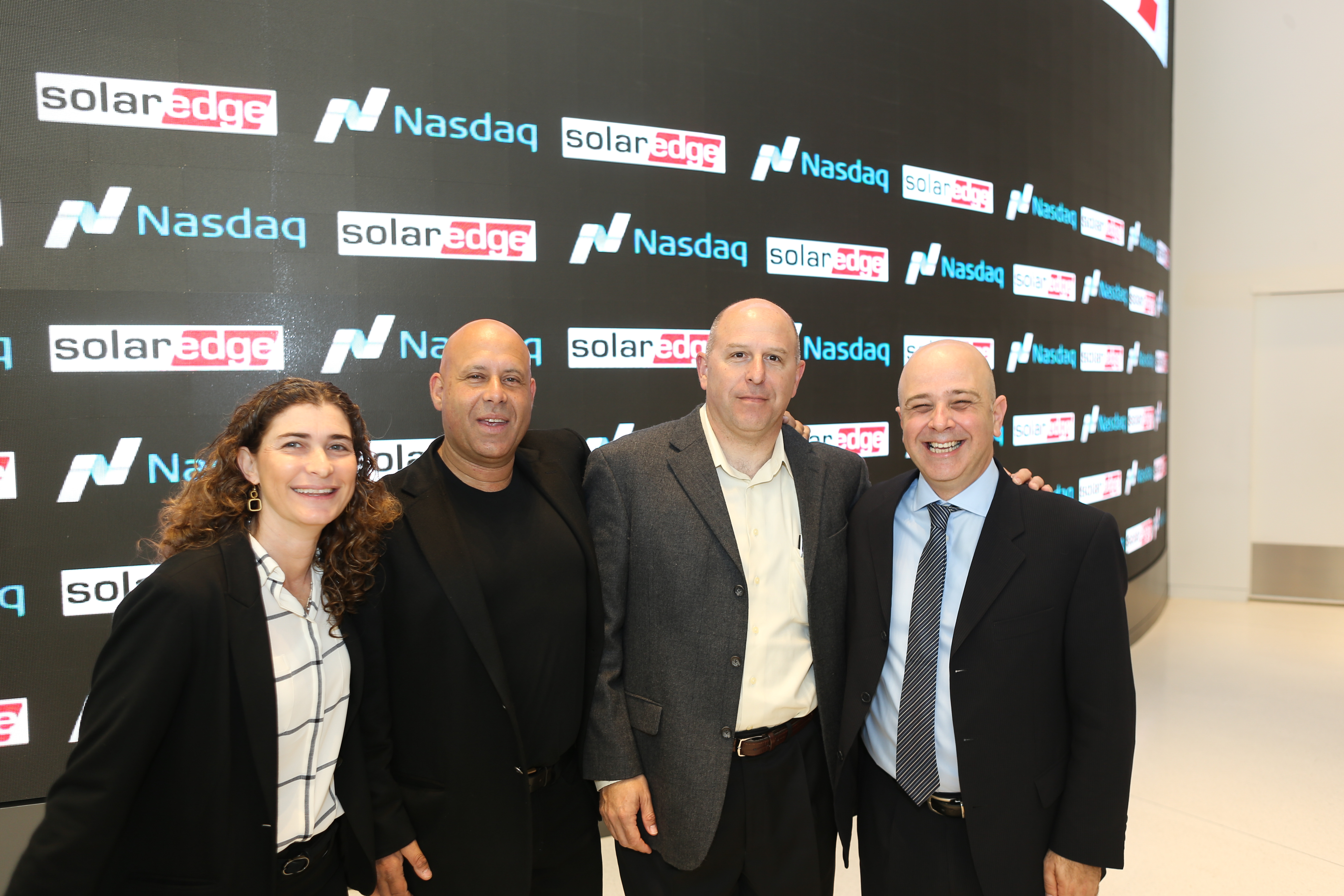 Guy Sella, second from left, and colleagues standing before a wall bearing Nasdaq and SolarEdge logos