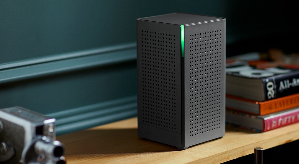 Black Calix router with a green status light, photographed beside books