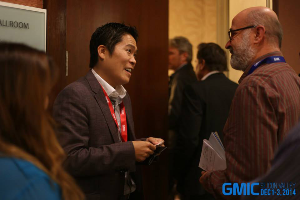 Two attendees talking in a hallway at GMIC Silicon Valley, in a photograph marked 2014