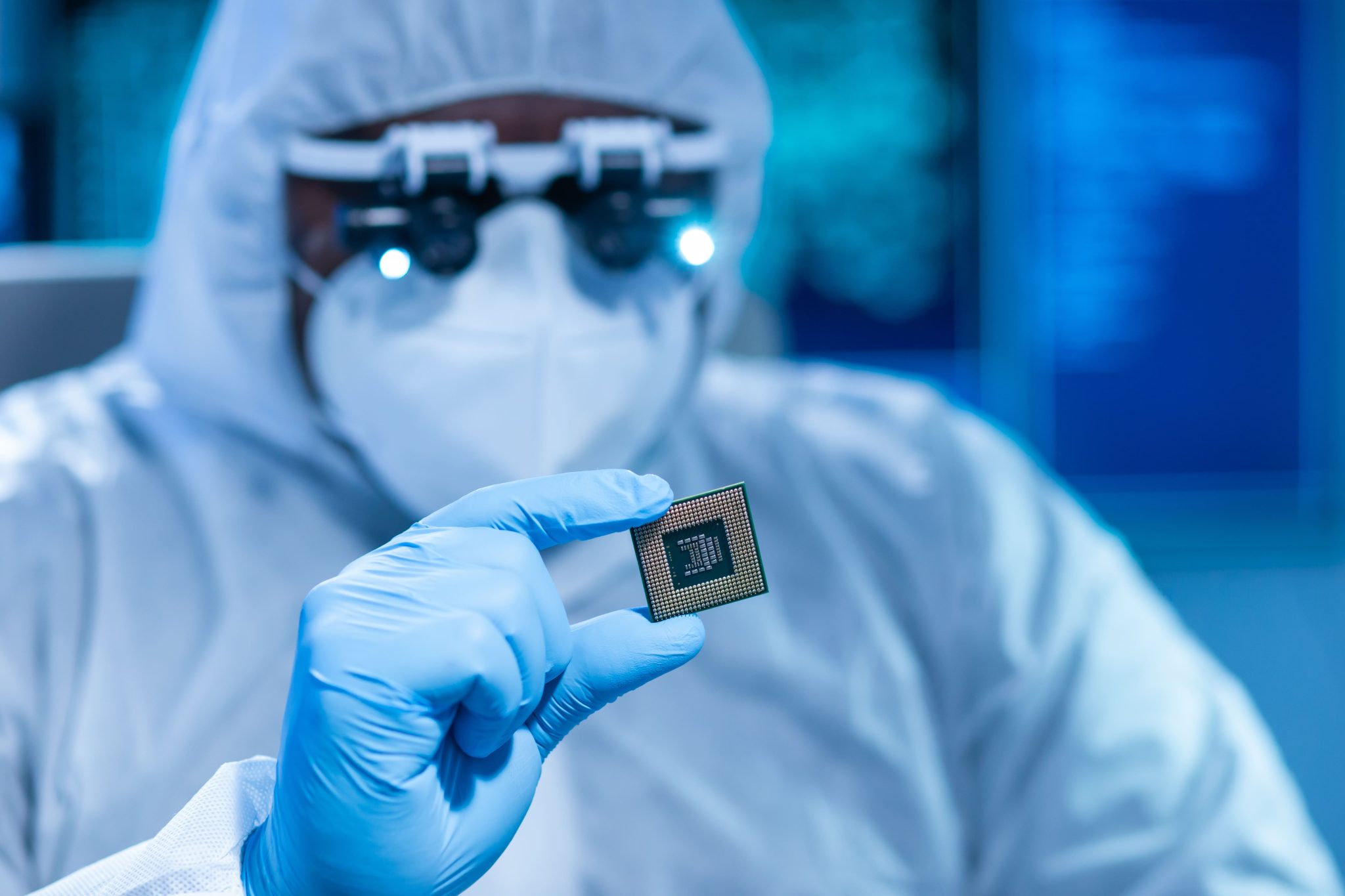 Illustrative cleanroom technician examining the underside of a semiconductor chip